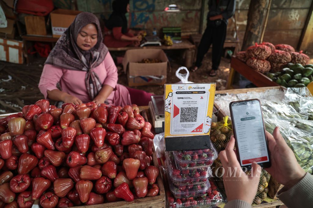 Iyut memanfaatkan kode respons cepat standar Indonesia atau QRIS untuk sistem pembayaran di lapak buahnya di kawasan Muncul, Tangerang Selatan, Banten, Minggu (10/9/2023).  