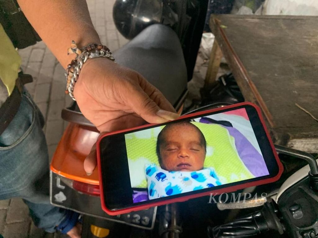 Al (50) menunjukkan foto bayi yang pernah ia rawat selama tiga bulan di Surabaya, Jawa Timur, Senin (27/3/2023), sebelum bayi itu diminta kembali ibu kandungnya.
