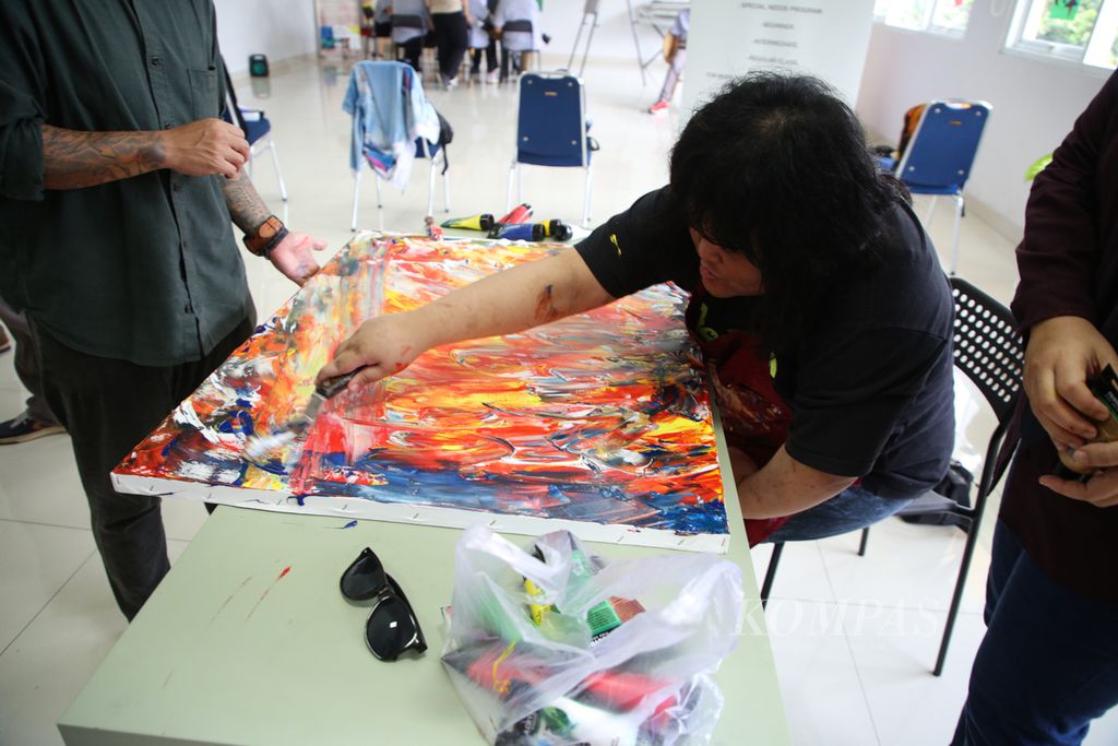 Indhy, anak dengan autis, tengah menyelesaikan lukisan yang akan diikuti pameran bersama di pusat pelatihan Matalesoge, Jakarta, Rabu (10/5/2023).