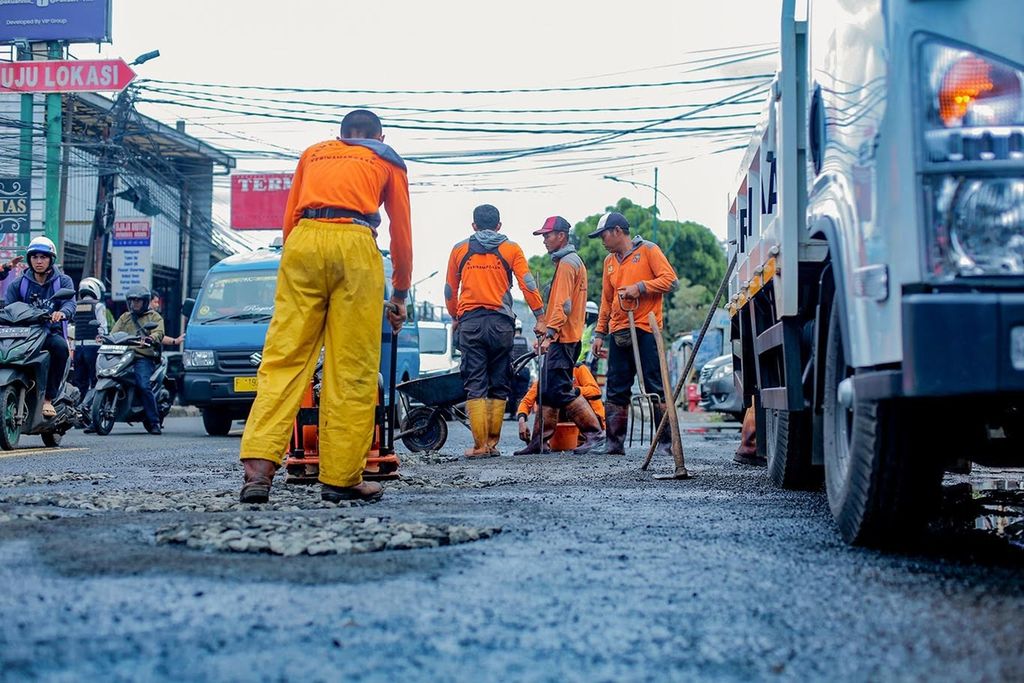 Petugas memperbaiki Jalan Raya Raya Tajur, Kota Bogor, yang rusak, Selasa (3/1/2022). 