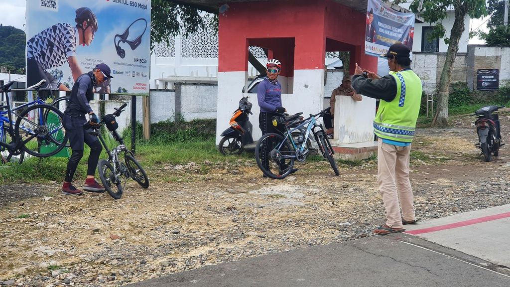 M Idris (45), juru parkir, membantu pesepeda berfoto di titik nol kilometer Sentul di Bojong Koneng, Jawa Barat, Sabtu (19/11/2022). 