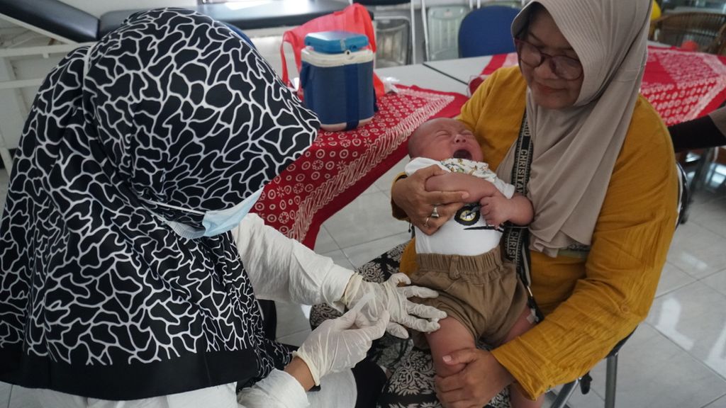 Niskala Bintang (4 bulan) dipangku oleh neneknya sedang disuntik untuk mendapatkan imunisasi di Posyandu Cempaka, RW 014, Karang Tengah, Kota Tangerang, Banten, Jumat (14/4/2023). 