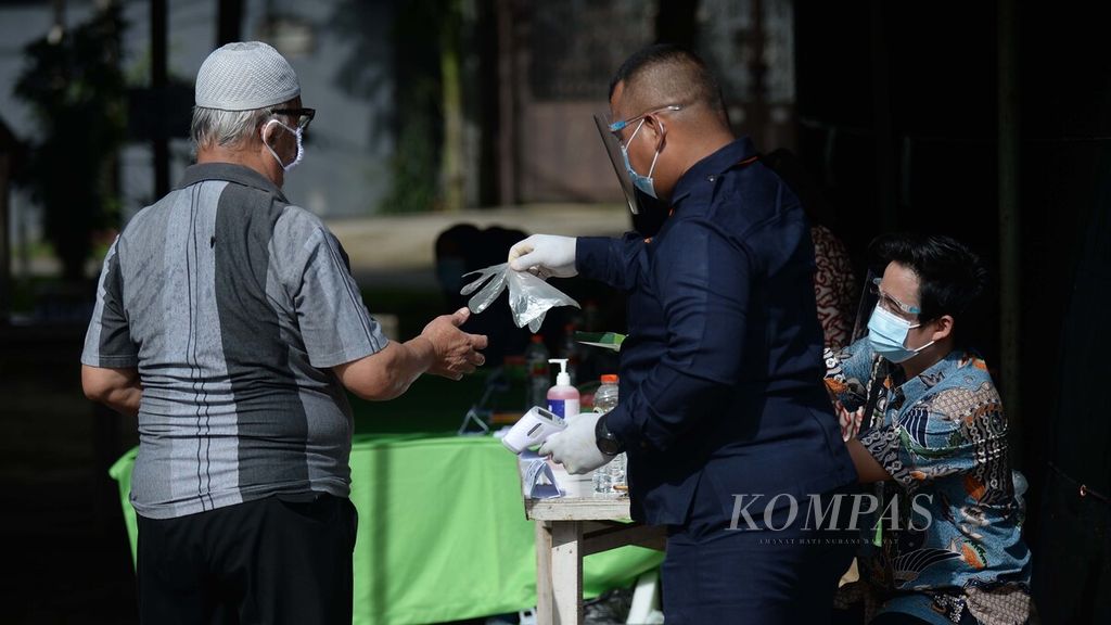 Petugas memberikan sarung plastik kepada warga yang akan memberikan hak suaranya pada Pilkada Kota Tangerang Selatan 2020 di TPS 79 Jurangmangu Barat, Pondokaren, Tangerang Selatan, Banten, Rabu (9/12/2020). 