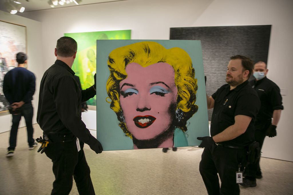Lukisan "Shot Sage Blue Marilyn," karya Andy Warhol dibawa petugas di Rumah Lelang Christie di New York, Minggu (8/5/2022). Lukisan itu terjual dalam lelang Senin (9/5), seharga 195 juta dollar Amerika Serikat. (AP Photo/Ted Shaffrey, File)