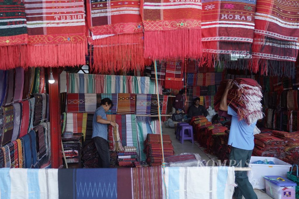 Pedagang kain ulos menata dagangannya di Pasar Balige, Kabupaten Toba, Sumatera Utara, Jumat (8/12/2023).