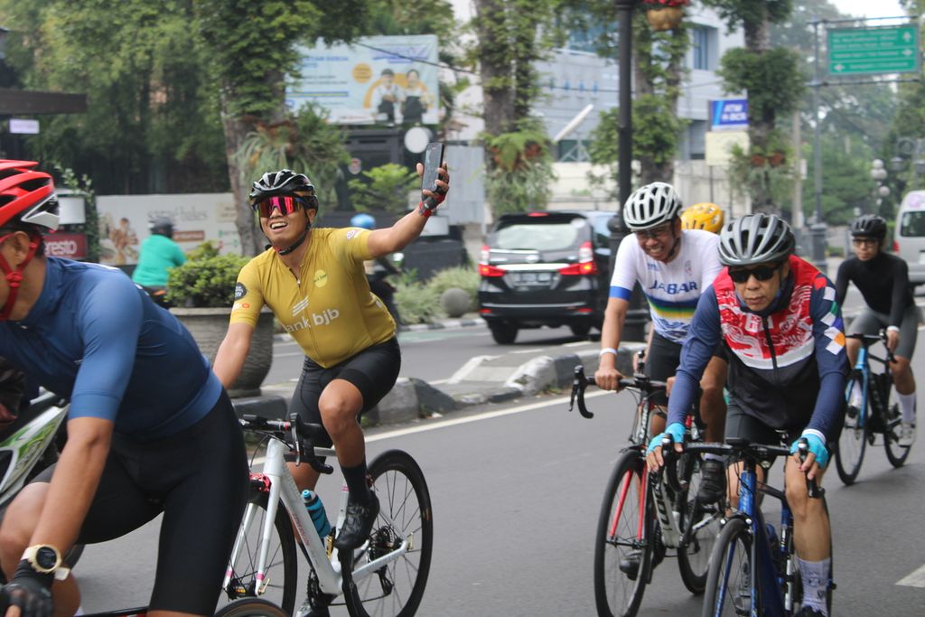 Salah satu peserta Coffee Ride Road to Cycling de Jabar 2024 mengabadikan momen dengan ponsel pintarnya saat berkendara di Jalan Ir H Juanda, Kota Bandung, Jawa Barat, Minggu (21/4/2024).