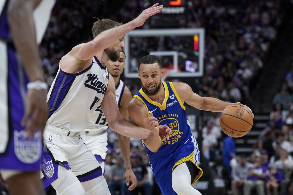 Golden State Warriors player, Stephen Curry (right), dribbles the ball while being blocked by Sacramento Kings player, Domantas Sabonis, during an NBA play-in match, Wednesday (17/4/2024) morning Indonesian time, in New Orleans. The Lakers won with a score of 110-106.