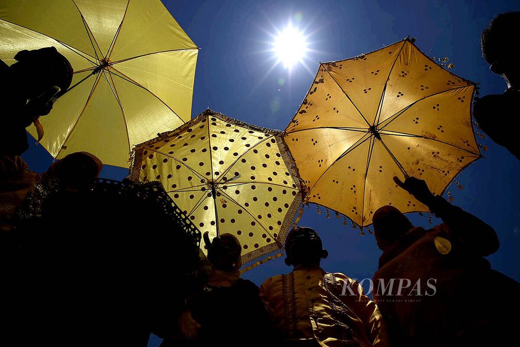 Warga mengenakan payung untuk mengindari terik matahari saat hadir dalam pembukaan Festival Gerhana Matahari Total di Desa Pakuli Utara, Kabupaten Sigi, Sulawesi Tengah, Minggu (6/3). Beragam aktivitas seni budaya diselenggarakan untuk menyambut gerhana Matahari total pada Rabu 9 Maret mendatang.
