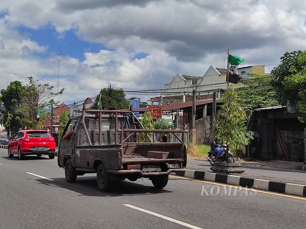 Mobil melintasi bendera suporter PS Sleman di Jalan Magelang KM 7, Mlati Beningan, Kabupaten Sleman, Daerah Istimewa Yogyakarta, Senin (8/8/2022). Bagi pendukung PSS, pemasangan bendera itu merupakan inisiatif suporter di wilayah setempat.