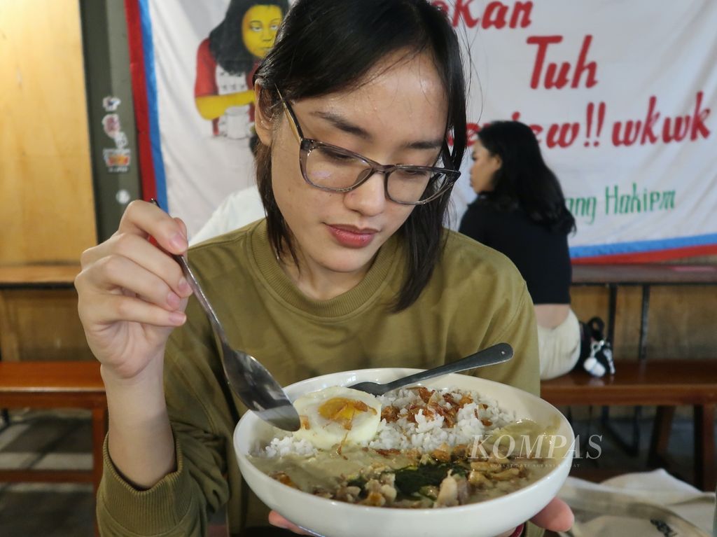 Salah seorang pengunjung Warpopski, Ril, mencicipi menu lodeh puree dengan <i>topping</i> ayam yang tersedia di Warpopski, warung nasi milik seniman Popo, di Tebet, Jakarta Selatan, Kamis (16/5/2024). Warpopski merupakan warung yang menyajikan masakan Indonesia <i>fusion</i>, dengan menu andalan nasi siram. Warpopski berdiri sejak 2017.