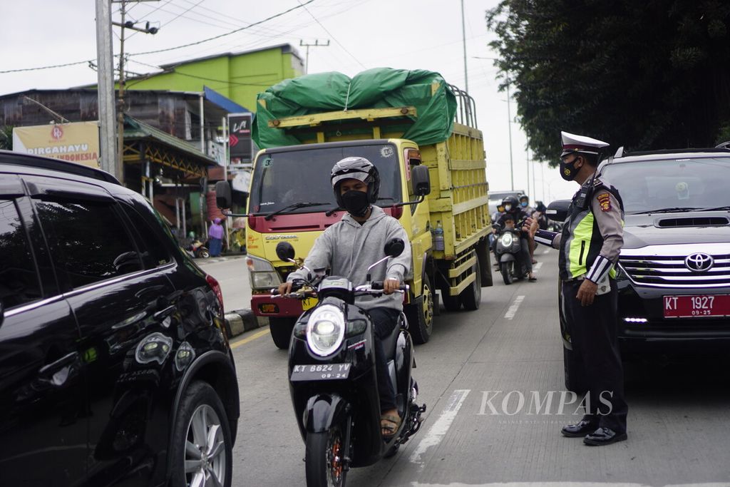 Polisi sedang mengatur lalu lintas kendaraan di jalan menurun kilometer 0 Jalan Soekarno Hatta di Simpang Muara Rapak, Kota Balikpapan, Kalimantan Timur, Minggu (23/1/2022). Jalan menurun ini termasuk titik rawan kecelakaan lantaran jalan yang menurun dan terdapat lampu merah di ujungnya.