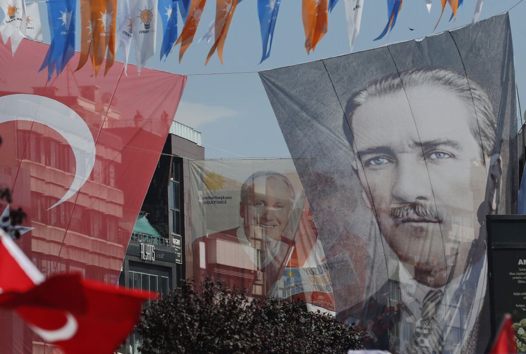Poster bergambar wajah Bapak Pendiri Republik Turki Mustafa Kemal Ataturk (kanan) dipajang bersebelahan dengan bendera Turki (kiri) serta poster kandidat presiden dari Partai Rakyat Republik, Moharrem Ince (tengah), dalam kampanye di Yalova, Turki, 14 Juni 2018. 