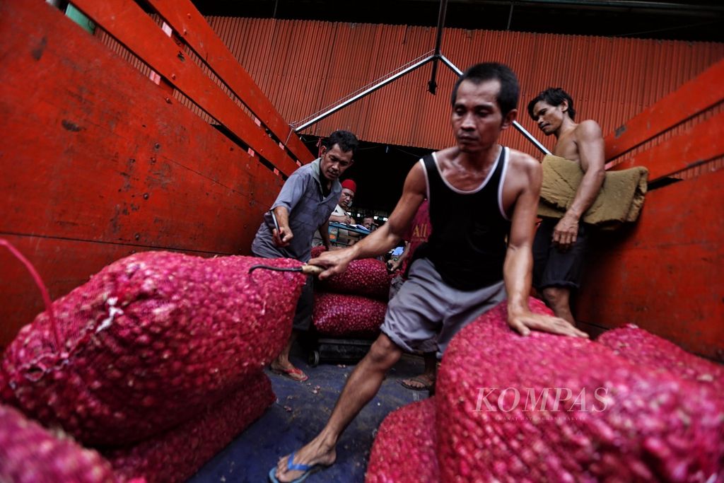 Buruh menurunkan karung berisi bawang merah yang baru datang dari Brebes, Jawa Tengah, di Pasar Induk Kramatjati, Jakarta Timur, Senin (28/3/2022). 