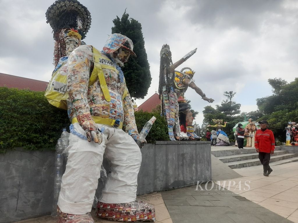 Seorang pengunjung berjalan di dekat patung-patung yang terbuat dari sampah plastik yang dipamerkan pada pergelaran 1001 Manusia Sampah di Balai Kota Among Tani, Kota Batu, Jawa Timur, Sabtu (23/7/2022).