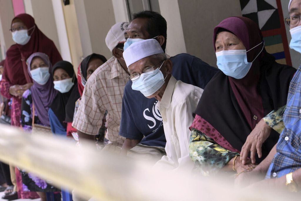 Para pemilih yang menggunakan masker untuk membantu mencegah penularan virus korona antre untuk kembali di tempat pemungutan suara, di Kota Kinabalu, Negara Bagian Sabah, Malaysia, Sabtu (26/9/2020). 