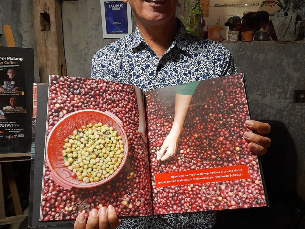 Prawoto Indarto, peneliti mandiri serta penulis buku soal kopi dan teh. Tampak Indarto menunjukkan isi buku keempatnya soal kopi, <i>Absolute Coffee</i>, di salah satu kafe di Malang, Jawa Timur, awal April 2022 lalu.