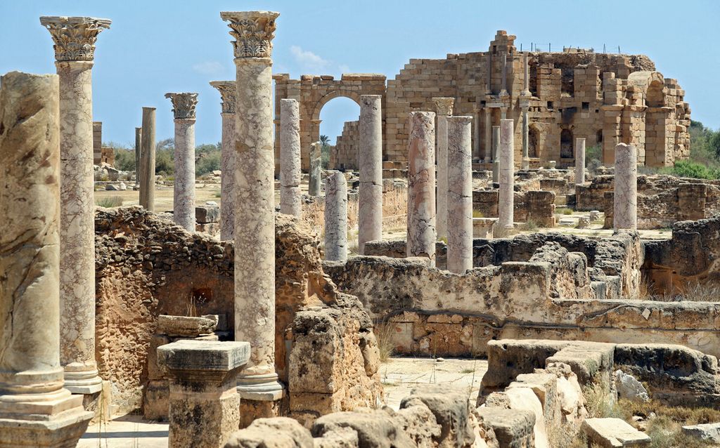 Kolom marmer yang menghadap ke arah Nymphaeum di latar belakang di kota Romawi kuno Leptis Magna, di kota pesisir Libya, Al-Khums. 