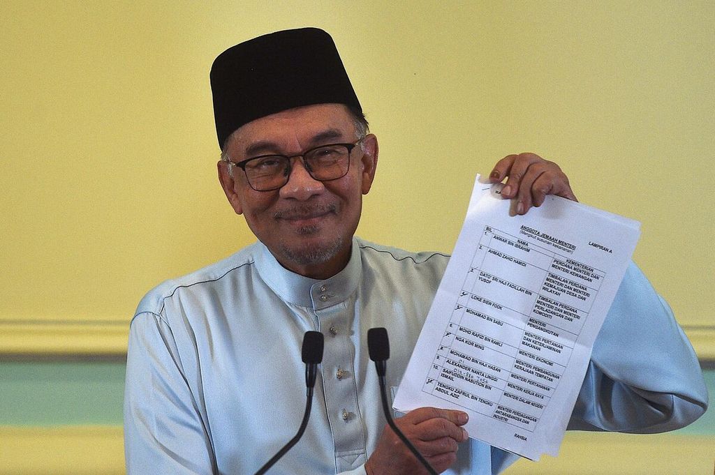 Perdana Menteri Malaysia Anwar Ibrahim memperlihatkan kertas berisi daftar menteri dalam kabinetnya saat mengumumkan susunan kabinet saat konferensi pers di kantor Perdana Menteri di Putrajaya, Malaysia, Jumat (2/12/2022). 