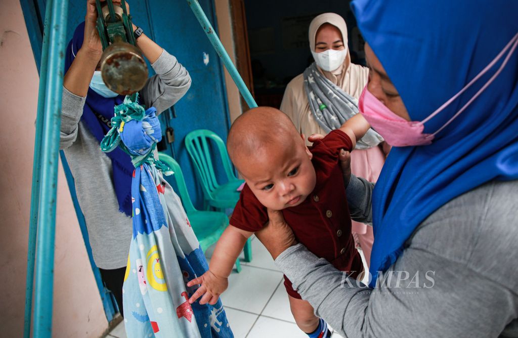 Kader posyandu menimbang bayi di Posyandu Mawar di RW 004 Kampung Bulak Wareng, Kota Tangerang, Banten, Jumat (8/4/2022).