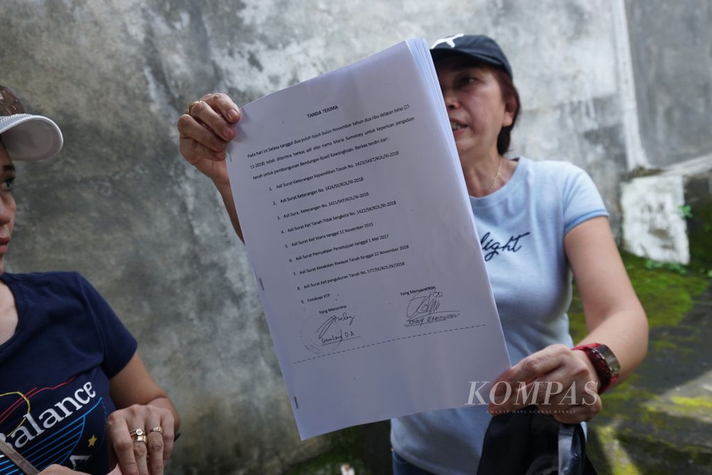 Sendie Sumarauw (52) menunjukkan dokumen hak warisnya atas sebuah tanah seluas 4 hektar, Kamis (19/1/2023), dalam protes di rumah mereka di Kecamatan Kalawat, Minahasa Utara, Sulawesi Utara. Lahan mereka kini telah menjadi bagian dari Bendungan Kuwil Kawangkoan yang diresmikan Presiden Joko Widodo pada hari yang sama.