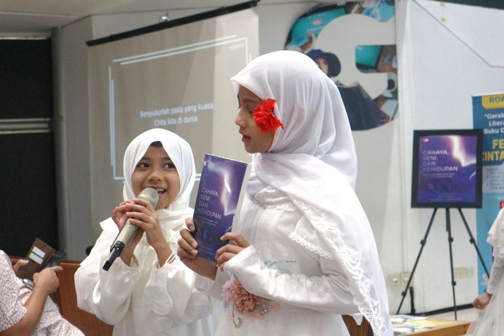 Dua  anak sedang menyanyi dan memamerkan buku <i>Cahaya, Seni, dan Kehidupan</i> dalam acara peluncuran buku tersebut yang diadakan di Gramedia Matraman, Jakarta Timur, Minggu (6/11/2022). Buku ini bergenre pengembangan diri.