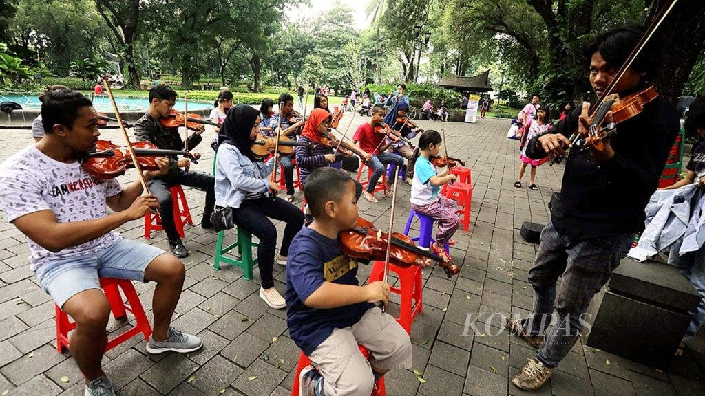 Sejumlah anggota komunitas Taman Suropati Chamber berlatih memainkan biola di Taman Suropati, Menteng, Jakarta Pusat, Minggu (20/1/2019). Taman kota yang nyaman tidak hanya menjadi paru-paru di tengah belantara beton Ibu Kota, tetapi juga dapat menjadi oase bagi warga.