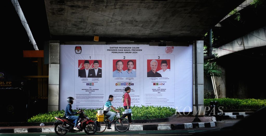 Warga melintasi poster sosialisasi bergambar para pasangan calon pemilihan presiden Pemilu 2024 di sekitar Jembatan Layang Kuningan-Mampang, Jakarta, Selasa (9/1/2024).