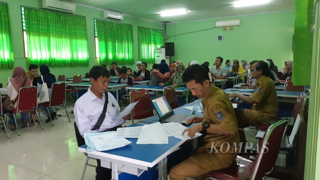 Panitia Penerimaan Peserta Didik Baru SMPN 3 Tangerang Selatan memeriksa kelengkapan berkas yang dibawa wali murid pada hari Senin (24/6/2019). Setelah itu, wali murid akan diberi kata sandi untuk mengakses laman PPDB dan mendaftarkan anaknya.