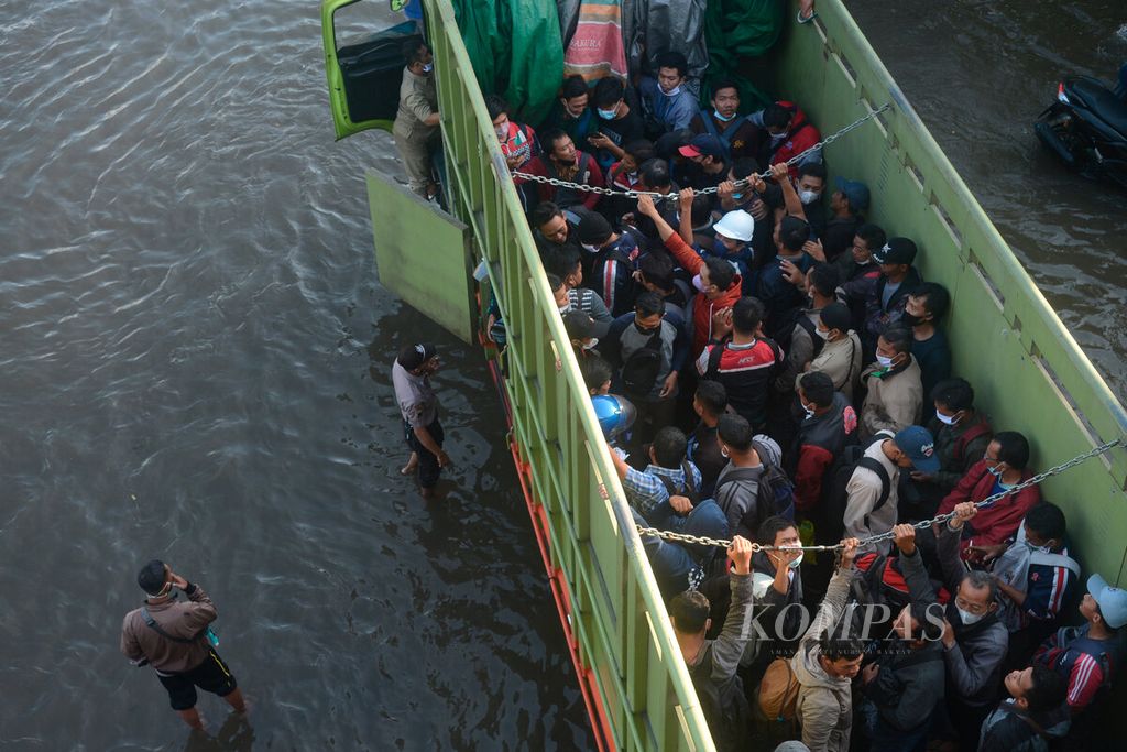 Pekerja berdesakan di dalam bak truk yang difungsikan sebagai transportasi menuju kawasan pelabuhan karena digenangi banjir pasang air laut di Pelabuhan Tanjung Emas, Kota Semarang, Jawa Tengah, Selasa (24/5/2022).  