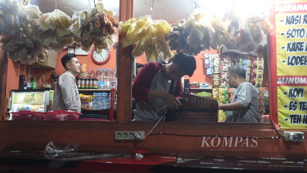 Pekerja memesan makanan saat jam pulang kantor di warung makan yang ada di sebuah gedung parkir di Jalan Embong Malang, Surabaya, Senin (26/2/2024). Saat ini sebagian besar kelas menengah usia 17-40 tahun kerepotan mengatur pengeluaran.