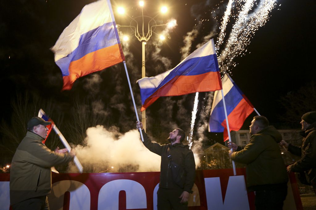 People wave Russian national flags to celebrate, in the center of Donetsk, the territory controlled by pro-Russian militants, eastern Ukraine, late Monday, Feb. 21, 2022. In a fast-moving political theater, Russian President Vladimir Putin has moved quickly to recognize the independence of separatist regions in eastern Ukraine in a show of defiance against the West amid fears of Russian invasion in Ukraine. 