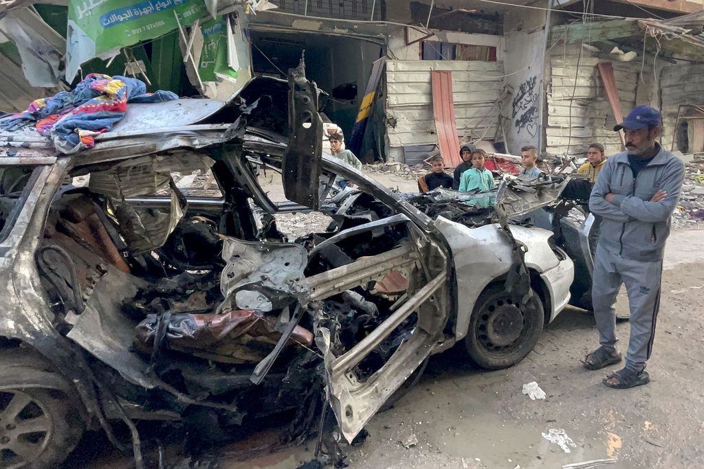 Sejumlah warga menyaksikan kendaraan yang menjadi korban serangan udara Israel di Al Shati, barat Kota Gaza, Rabu (10/4/2024). Tiga anak pemimpin Hamas, Ismail Haniyeh, meninggal dalam serangan Israel tersebut. 
