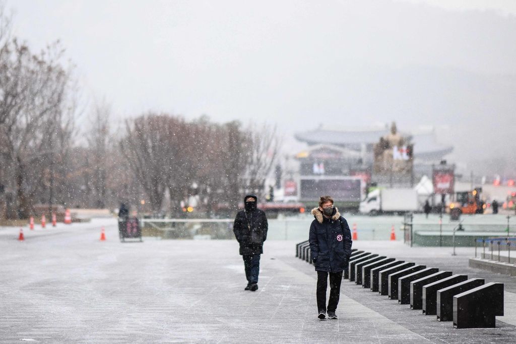 Warga berjalan kaki di Gwanghwamun Plaza saat salju turun di Seoul, Korea Selatan, 6 Desember 2022.