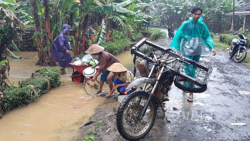 Warga Dusun Rowotrate, Desa Sitiarjo, Kecamatan Sumbermanjing Wetan, Kabupaten Malang, Jawa Timur, membersihkan peralatan dapur yang terdampak banjir menggunakan air sisa-sisa banjir di tepi jalan, Selasa (18/10/2022).