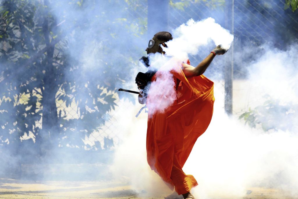 Pengunjuk rasa melemparkan kembali kaleng gas air mata yang ditembakkan polisi yang membubarkan protes di Colombo, Sri Lanka, 9 Juli 2022. 