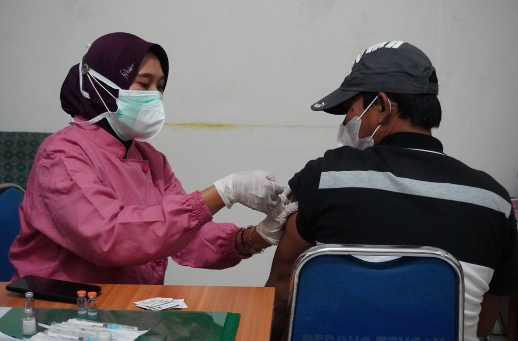 Tenaga kesehatan menyuntikkan vaksin jenis Sinovac kepada warga di kantor Kelurahan Debong Tengah, Kecamatan Tegal Selatan, Kota Tegal, Jawa Tengah, Jumat (11/9/2021) malam. 