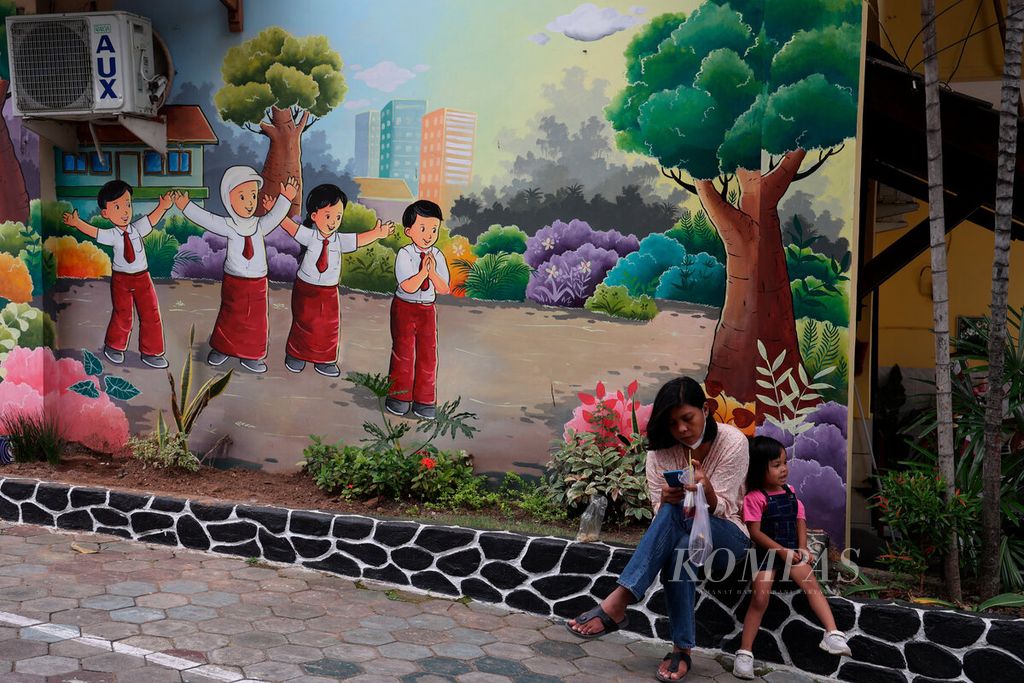 Orangtua siswa yang menunggu anaknya pulang sekolah dengan latar belakang lukisan mural di SD Candi 1, Kota Semarang, Jawa Tengah, Selasa (1/11/2022).