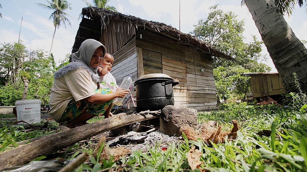 Nur Ismi (30) memasak menggunakan kayu bakar di halaman belakang rumahnya di Gampong Lamcarak, Kecamatan Seulimum, Kabupaten Aceh Besar,  Aceh, Sabtu (14/1). Kesulitan ekonomi membuat keluarga Nur tak mampu membeli bahan bakar minyak atau gas. Sehari-hari, Nur bekerja sebagai pembuat kue dengan penghasilan Rp 15.000-Rp 20.000 per hari. Suaminya, Tarmizi (35), buruh bangunan.