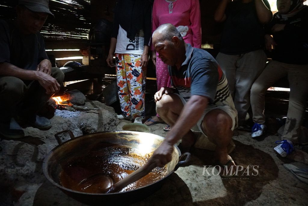 Hendrik Bonde, seorang petani gula aren, mengaduk adonan nira yang telah mengental dalam proses pembuatan gula semut, Selasa (19/7/2022), di Desa Tapa Aog, Lolayan, Bolaang Mongondow, Sulawesi Utara.