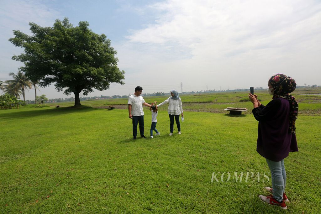 Pengunjung berfoto dengan latar areal persawahan saat menikmati suasana piknik di Padi-Padi Picnic Ground di Pakuhaji, Kramat, Kecamatan Pakuhaji, Kabupaten Tangerang, Banten, Selasa (15/2/2022). 