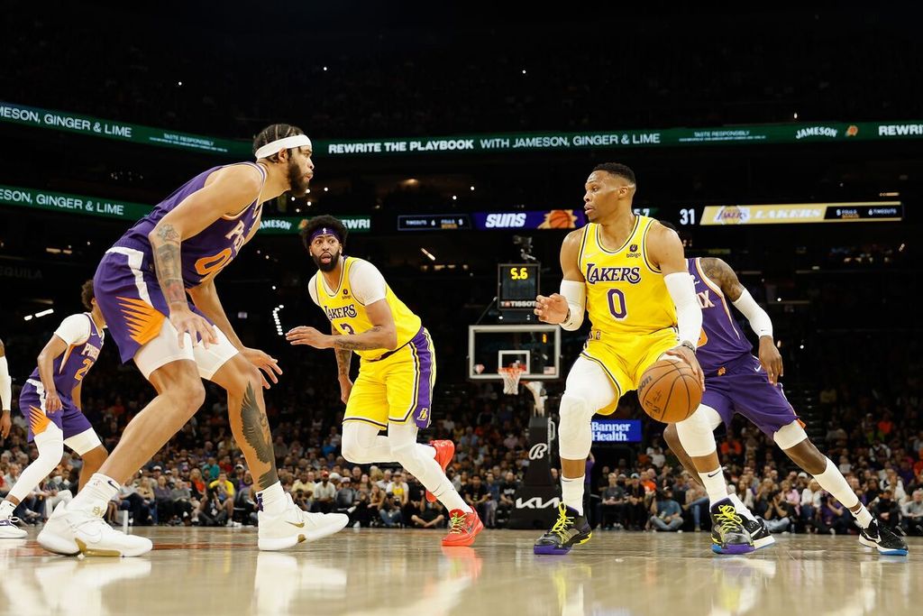 Pemain LA Lakers, Russell Westbrook (0), mendribel bola mencoba melewati pemain Phoenix Suns, JaVale McGee (00), dalam pertandingan NBA antara Lakers dan Suns di Footprint Center, Phoenix, Arizona, Rabu (6/4/2022) WIB. 