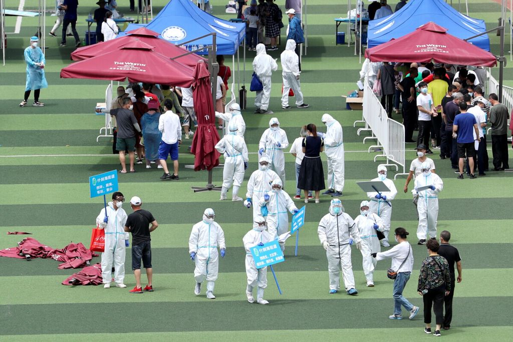 Pekerja medis dengan pakaian pelindung membantu orang-orang yang mengantre di dalam pusat olahraga untuk tes Covid-19, menyusul kasus infeksi baru penyakit Covid-19 di Beijing, Chinam, 15 Juni 2020. 