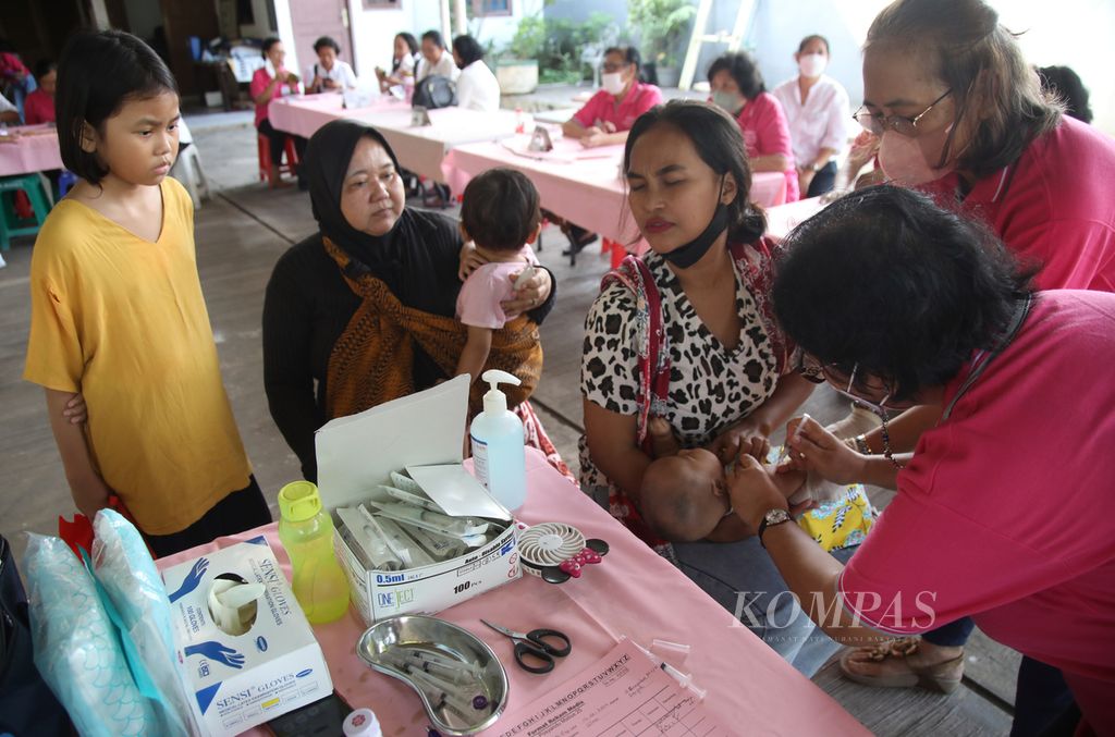 Bidan menyuntikkan vaksin ke lengan seorang balita dalam layanan Screening Balita (Posyandu) Matius 25 yang digelar di halaman Polimat Gereja Santo Matius Penginjil di kawasan Pondok Aren, Tangerang Selatan, Minggu (14/5/2023). Sebanyak 47 anak balita mendapat pelayanan di posyandu ini.