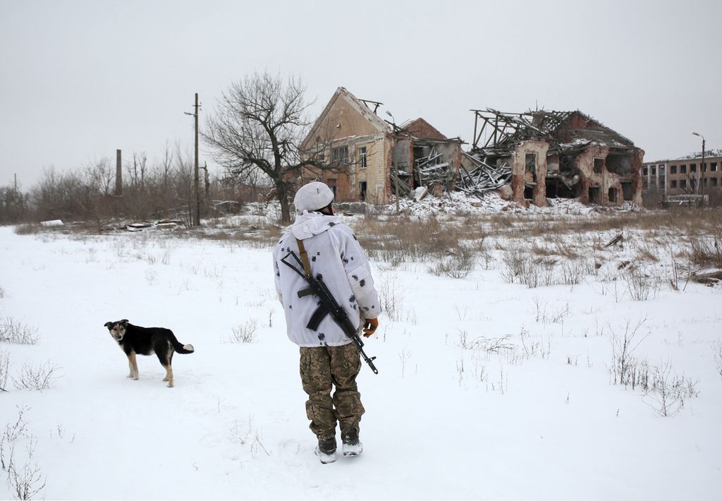 Seorang anggota pasukan Ukraina berjalan bersama anjingnya di garis depan wilayah yang dikuasai kelompok separatis yang didukung Rusia di Desa Peski, Donetsk, Ukraina timur, Selasa (25/1).