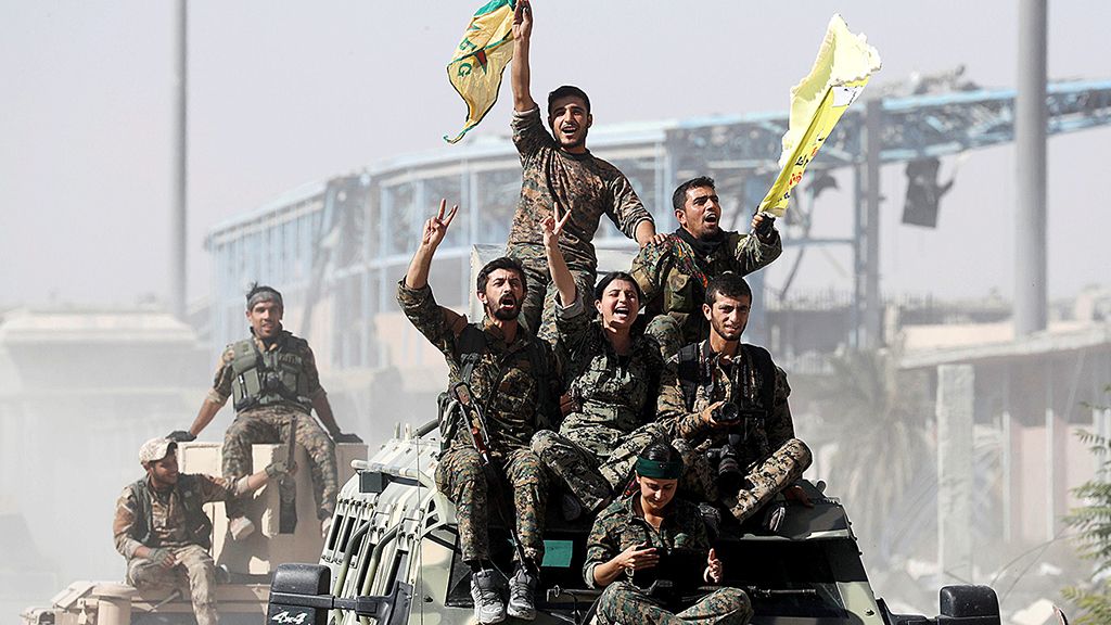 Milisi Pasukan Demokratik Suriah (SDF) naik di atap kendaraan militer saat merayakan kemenangan di Raqqa, Suriah, Selasa (17/10). Tantangan terbesar sekarang adalah membangun kembali kota yang sebelumnya dikuasai kelompok  Negara Islam di Irak dan Suriah (NIIS) itu. 