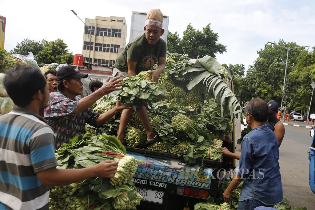 Buruh di Pasar Senen, Jakarta Pusat, membongkar sayur mayur yang didatangkan dengan angkutan bak terbuka dari Sukabumi, Senin (24/10/2022). 