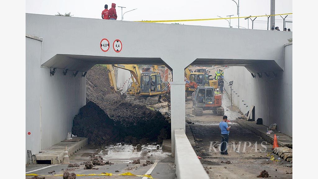 Alat berat digunakan untuk membersihkan material dinding penahan tanah yang ambrol di Jalan Perimeter Selatan, kompleks Bandara Soekarno-Hatta, Tangerang, Selasa (6/2). Akibat longsor ini, satu orang tewas dan seorang terluka. Selain itu, longsor ini juga membuat kereta bandara berhenti beroperasi.