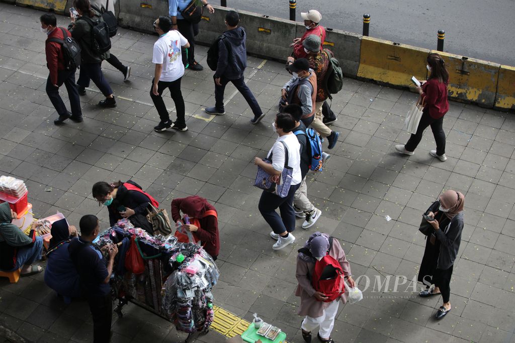 Para pekerja, baik sektor formal maupun informal, melintas di jalur pedestrian di Jalan Blora, Jakarta, setelah keluar dari Stasiun Sudirman, Rabu (4/1/2022). 