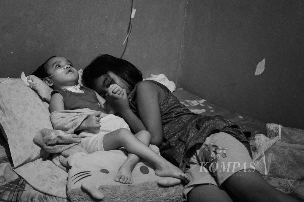Nafila (12) menemani Nasifa (3) di rumah mereka di Kota Batam, Kepulauan Riau, Senin (3/7/2023). Anak itu menjalani perawatan di rumah setelah dinyatakan pulih dari gangguan ginjal akut progresif atipikal (GGAPA) pada Januari.