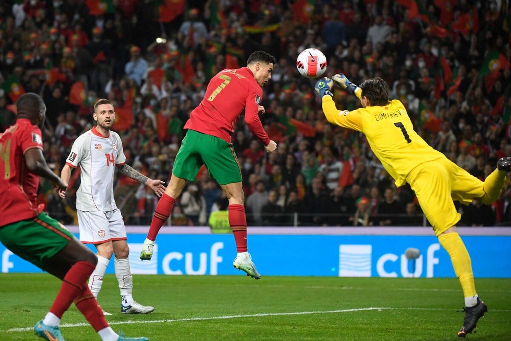 Pemain timnas Portugal Cristiano Ronaldo (tengah) berebut bola dengan kiper Macedonia Utara Stole Dimitrievski pada laga final penyisihan Piala Dunia di Stadion Dragao, Porto, Portugal, Rabu (30/3/2022) dini hari WIB. Portugal menang dengan skor 2-0.